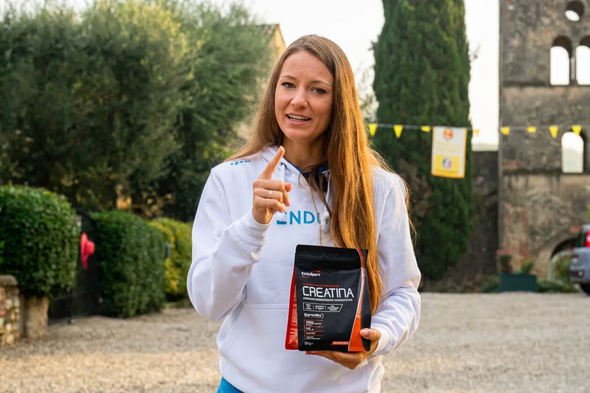 Presentatrice in felpa ENDU mostra una confezione di creatina EthicSport tenendo l'indice alzato mentre parla
