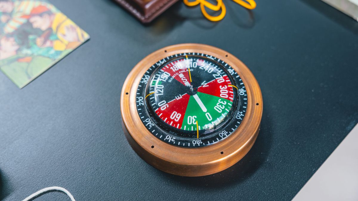Una bussola Suunto d'epoca con la cassa in rame e il quadrante rosso, verde e nero esposta sul tavolo della mostra