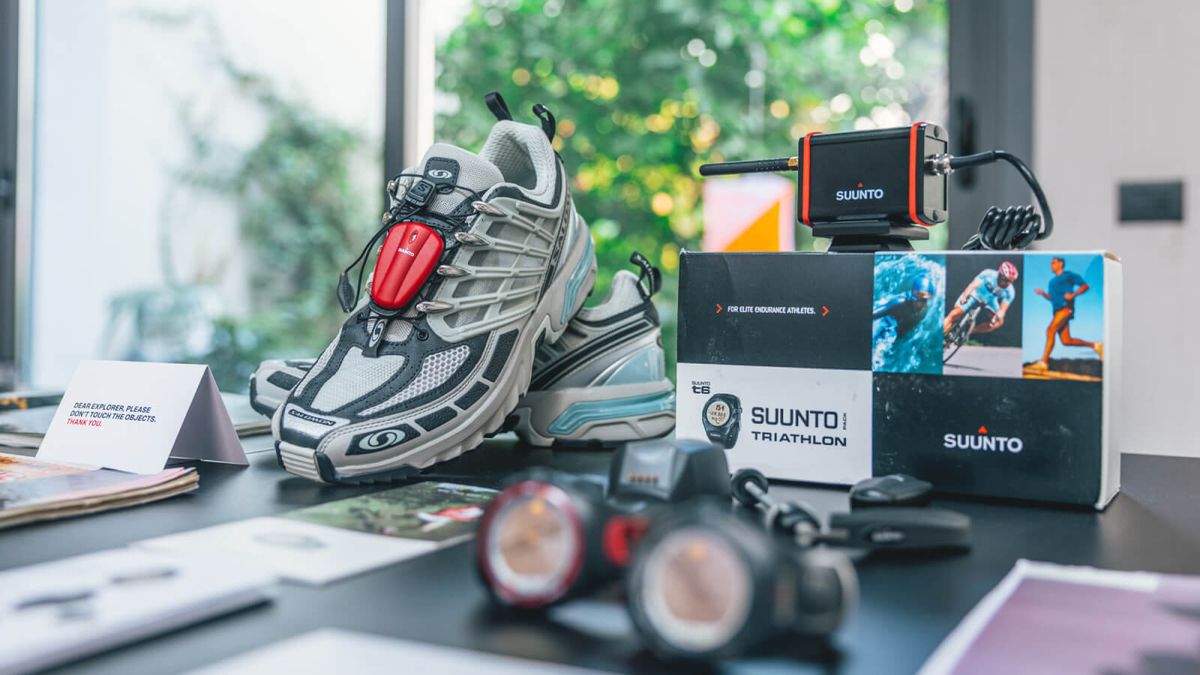 Scarpe da trail con un sensore rosso sui lacci accanto alla confezione del Suunto t6 Triathlon e ad altri strumenti d'archivio