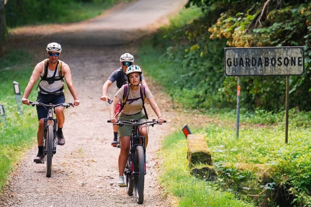 Tre persone in e-bike su una strada sterrata all ingresso del borgo di Guardabosone, in Valsesia